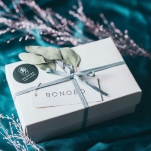 4. BONOBO gift box wrapped with ribbon and eucalyptus on teal fabric