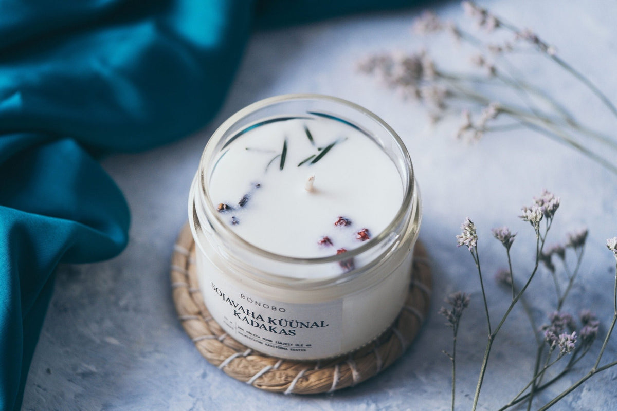 3. Open BONOBO juniper candle with visible herbs on textured surface with teal fabric