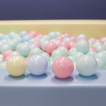 2. Studio shot of IGLU pastel ball pit balls in pink, blue, and yellow, arranged in a row with more balls in the background