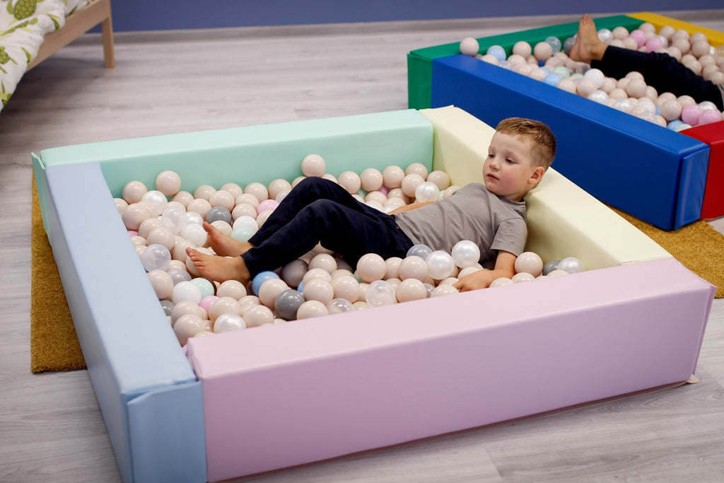 2. Child relaxing in IGLU light pastel foam ball pit filled with pastel balls indoors