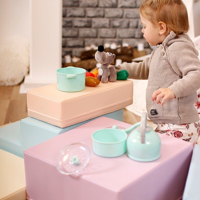 22. Child playing with toys on IGLU pastel foam blocks, promoting creativity and social skills