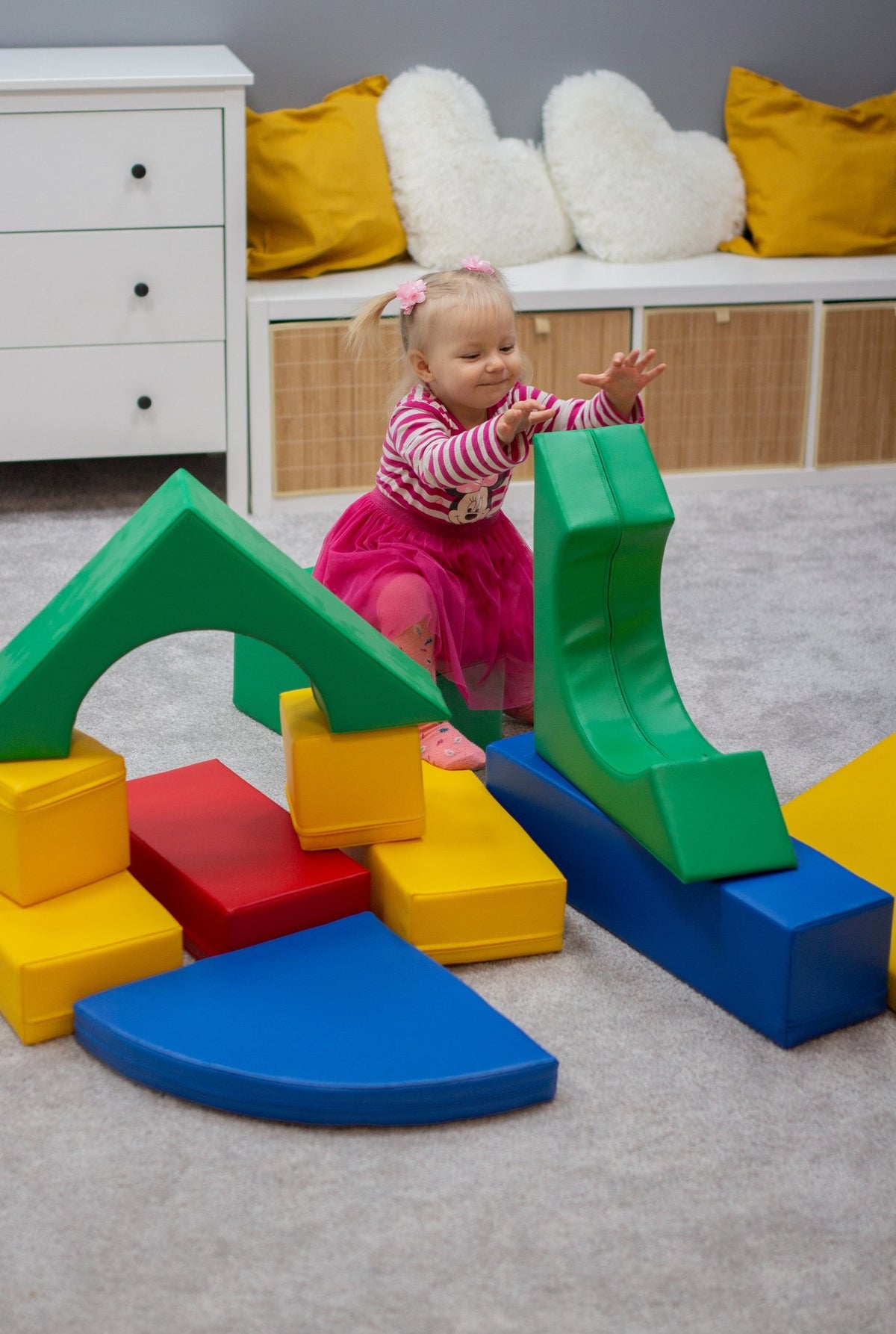 8. Girl arranging multicolor foam blocks on a carpeted floor in a playroom
