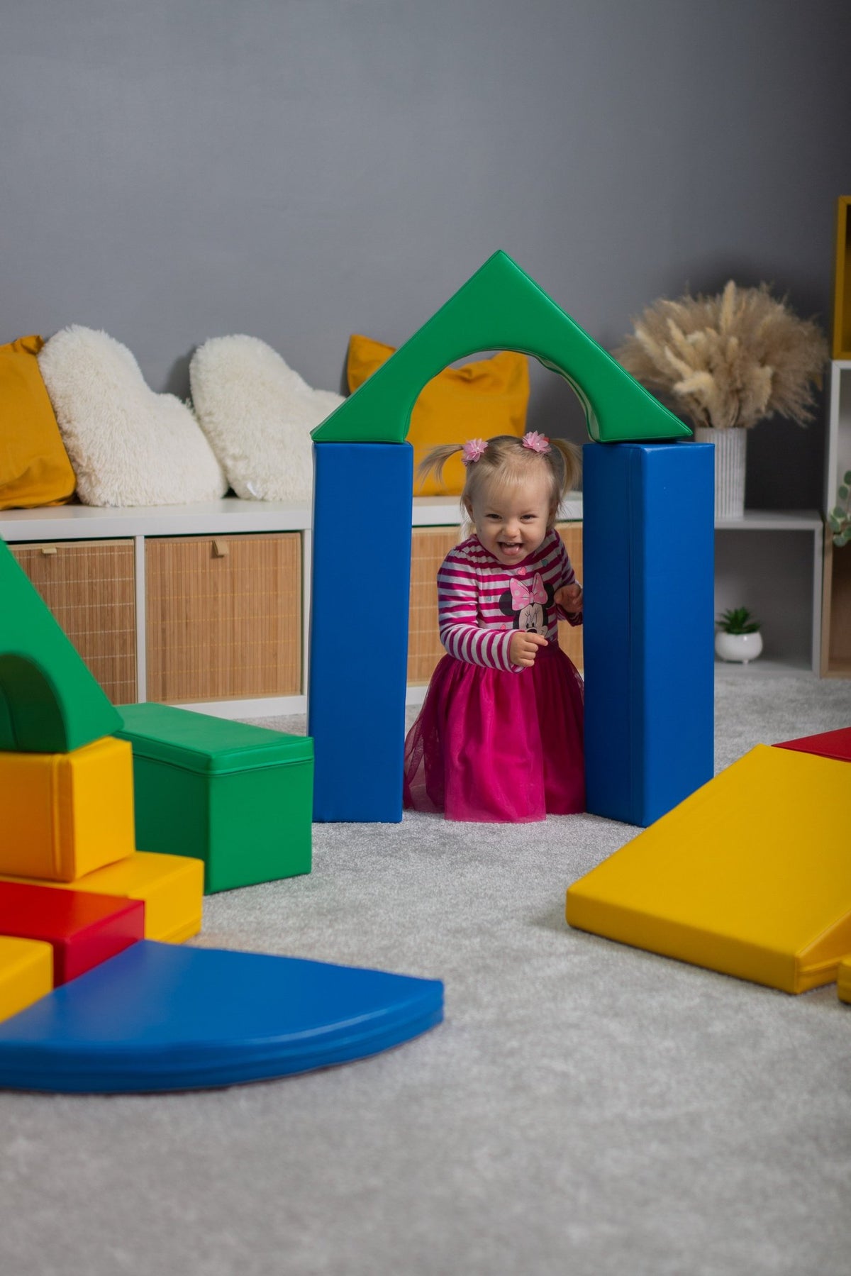 6. Girl standing inside archway made of multicolor foam blocks in a playroom