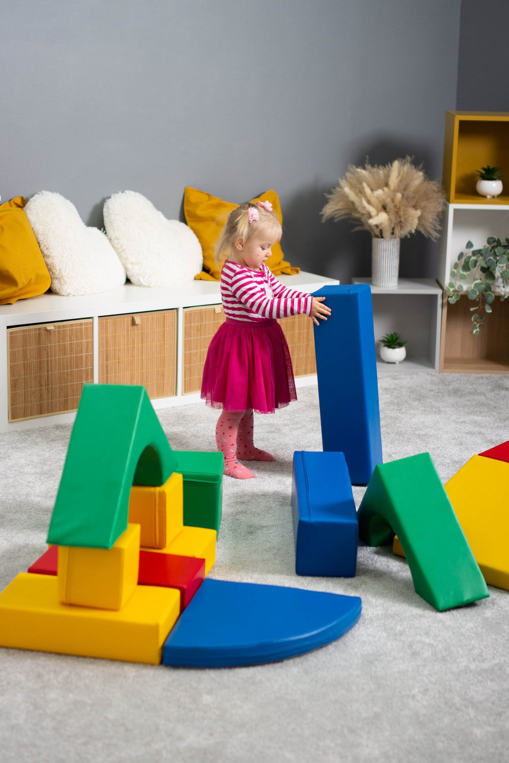 3. Girl in pink dress building with multicolor foam blocks in a playroom