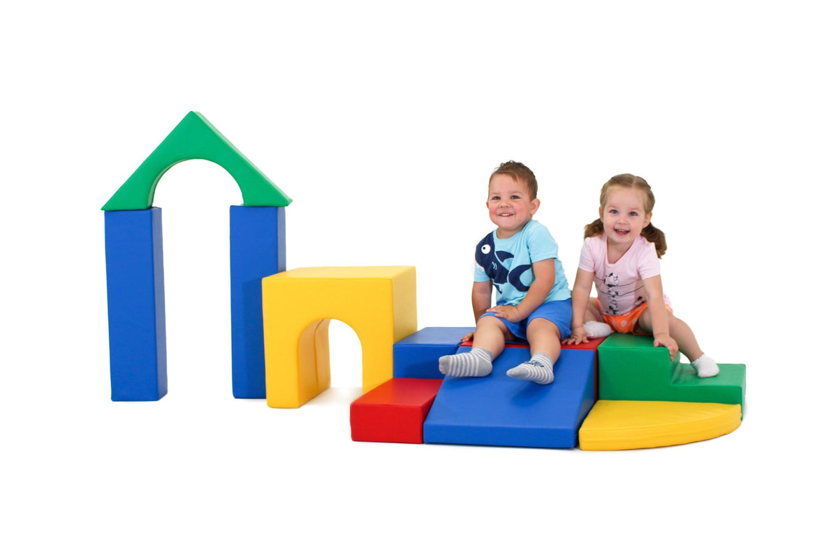 13. Two children sitting on multicolor foam blocks with archway in background
