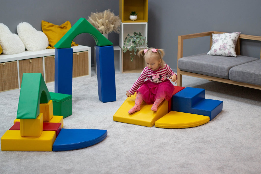 4. Girl sitting on yellow foam block steps surrounded by multicolor blocks in a playroom