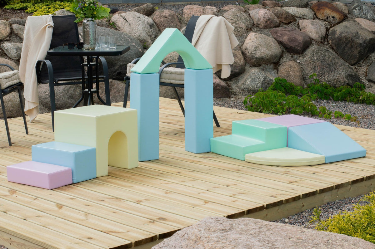 1. Pastel foam blocks arranged outdoors on a wooden deck with patio furniture in the background