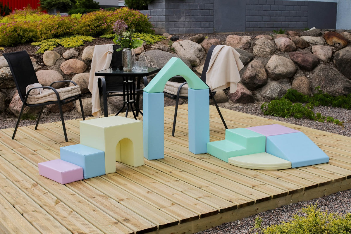 1. Outdoor setup of pastel foam blocks on a wooden deck with stone wall backdrop