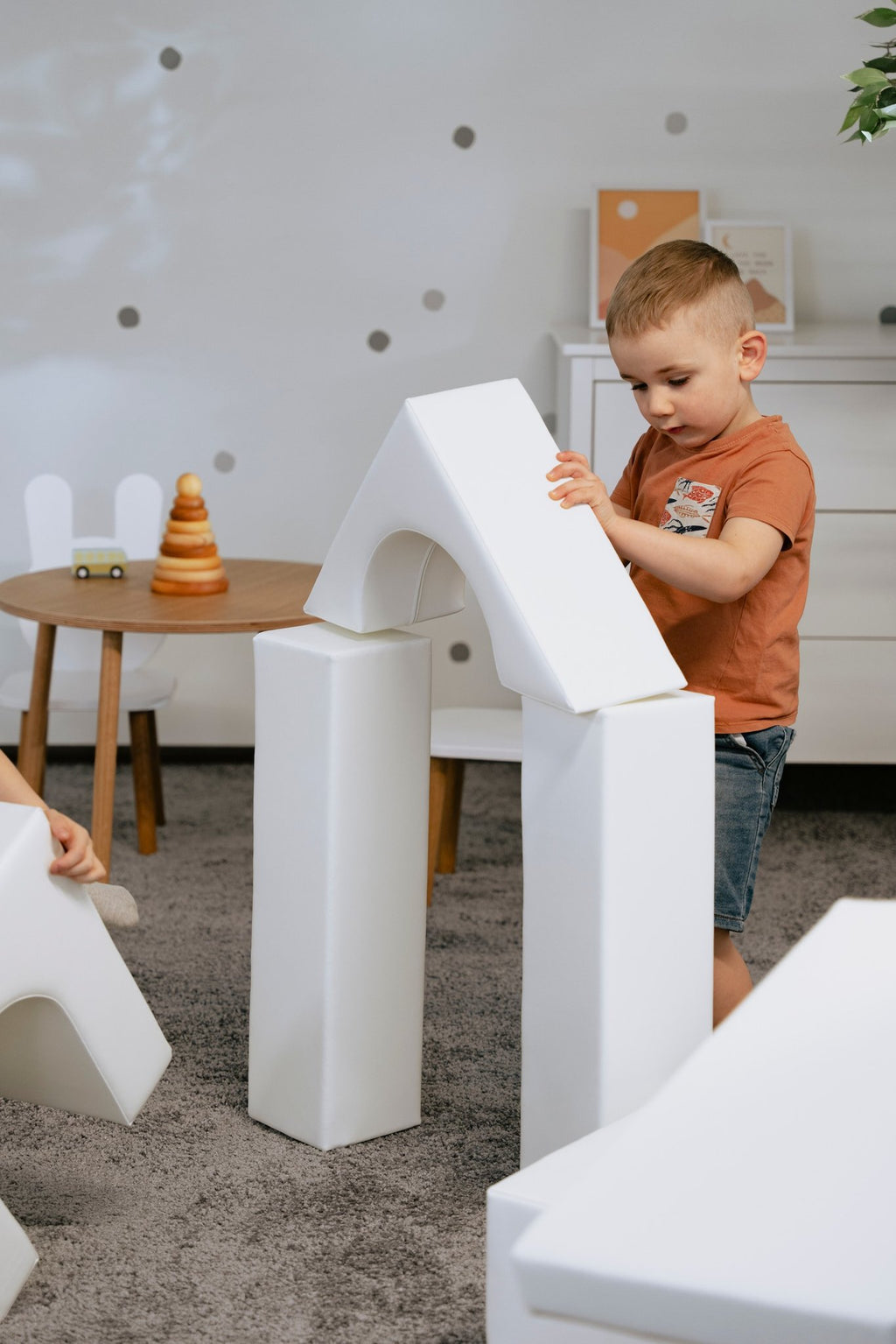 1. Child building with white foam blocks in a playroom, part of IGLU Adventurer set