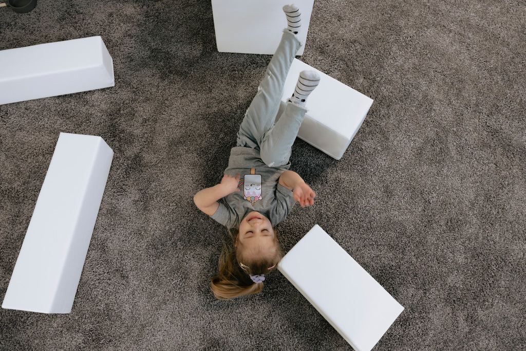 1. Child lying on the floor surrounded by white foam blocks, part of IGLU Adventurer set