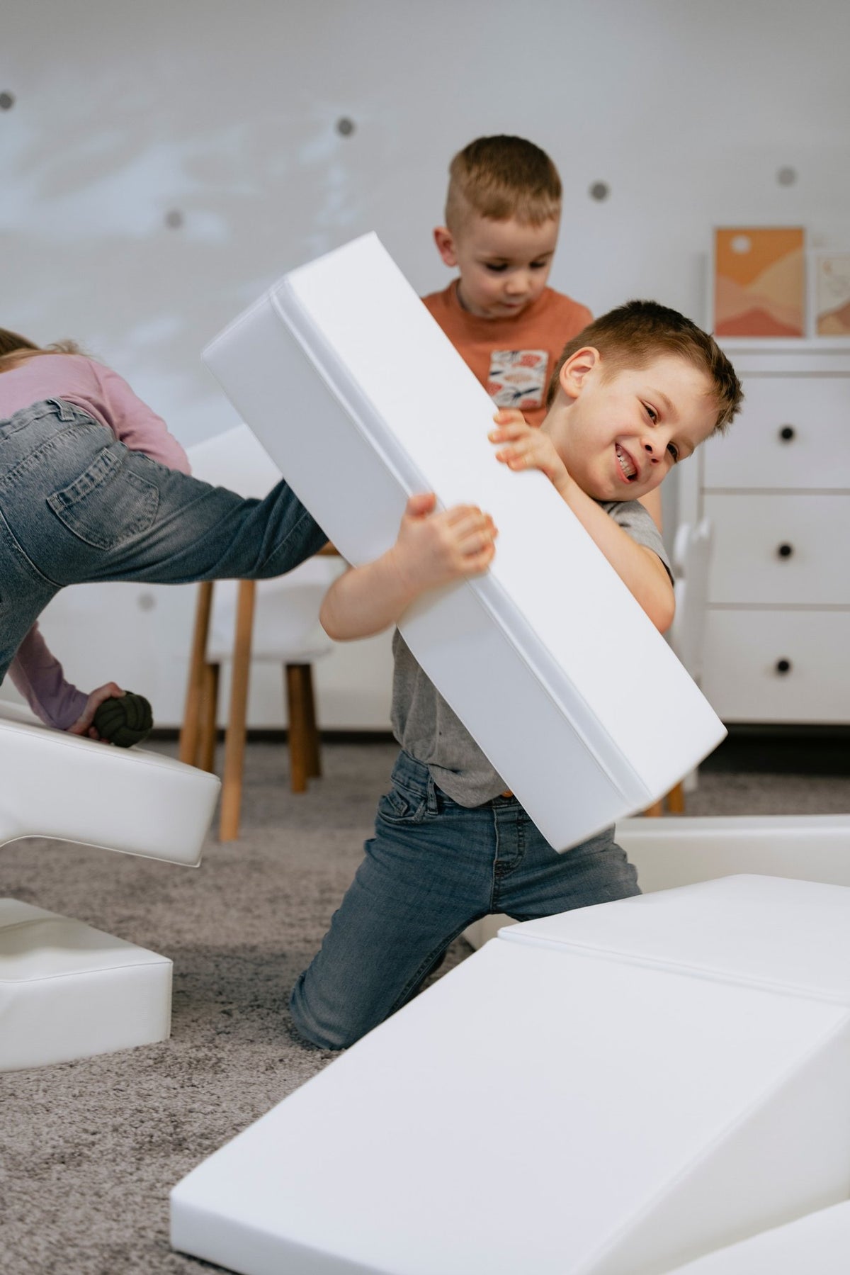 1. Children playing energetically with white foam blocks in a playroom, part of IGLU Adventurer set