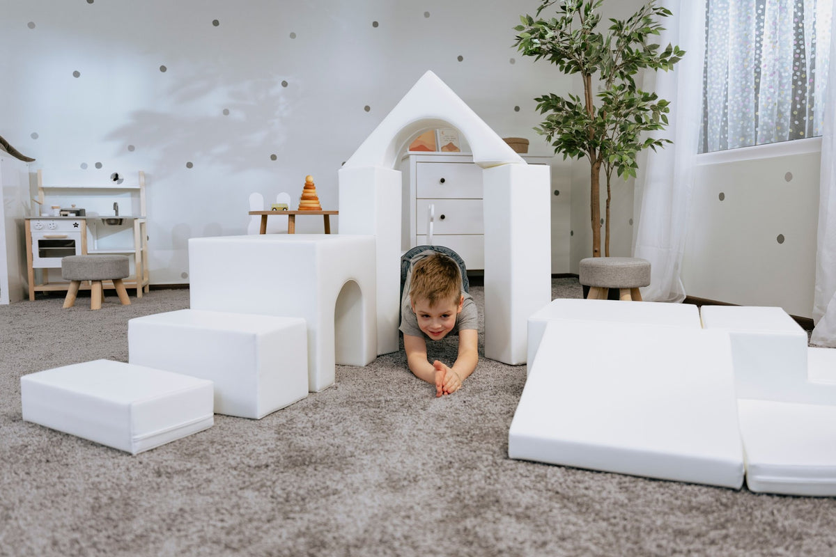 1. Child crawling through white foam block tunnel in a playroom setting with IGLU Adventurer playset
