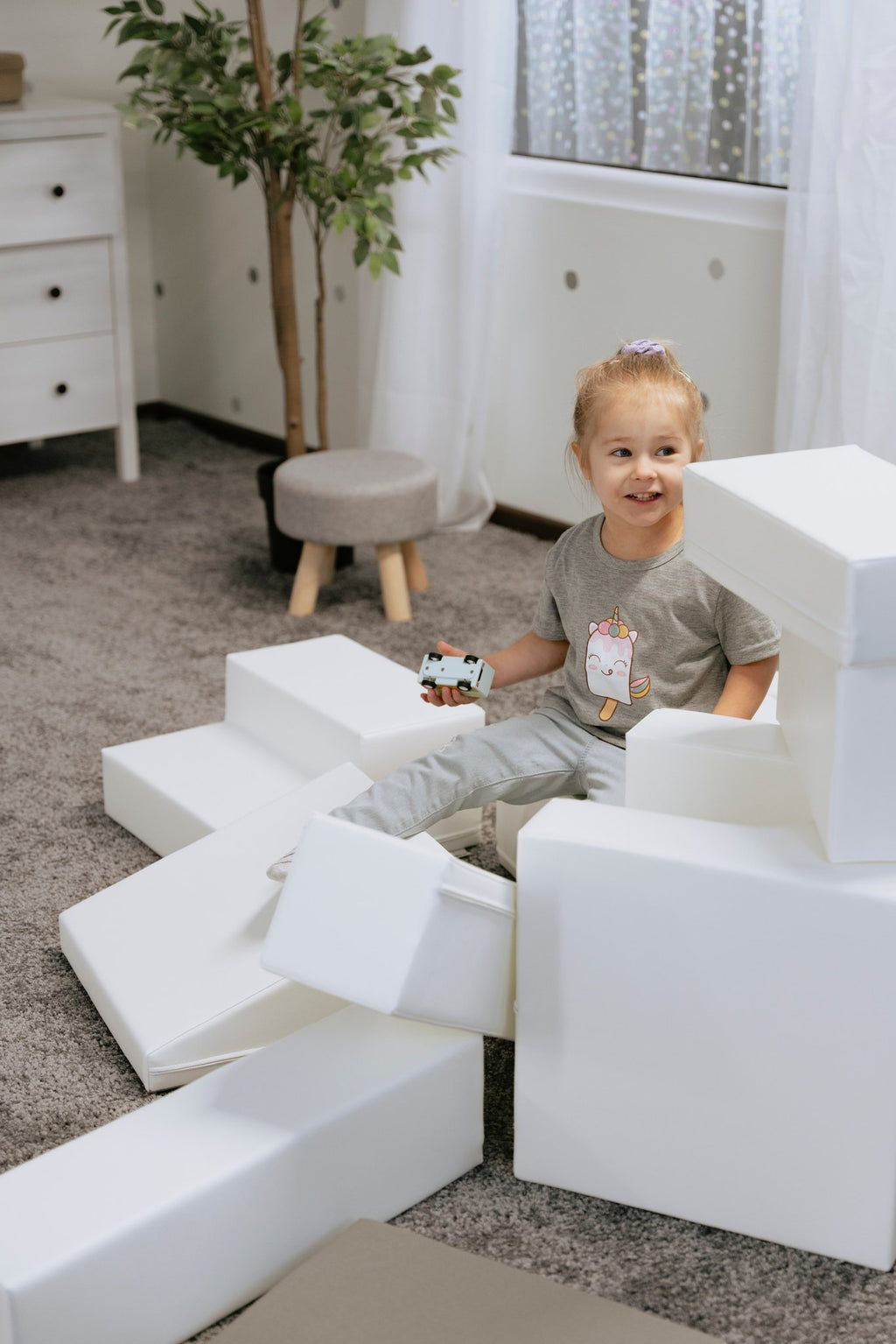 1. Child sitting on white foam blocks in a playroom, part of IGLU Adventurer 10-piece set