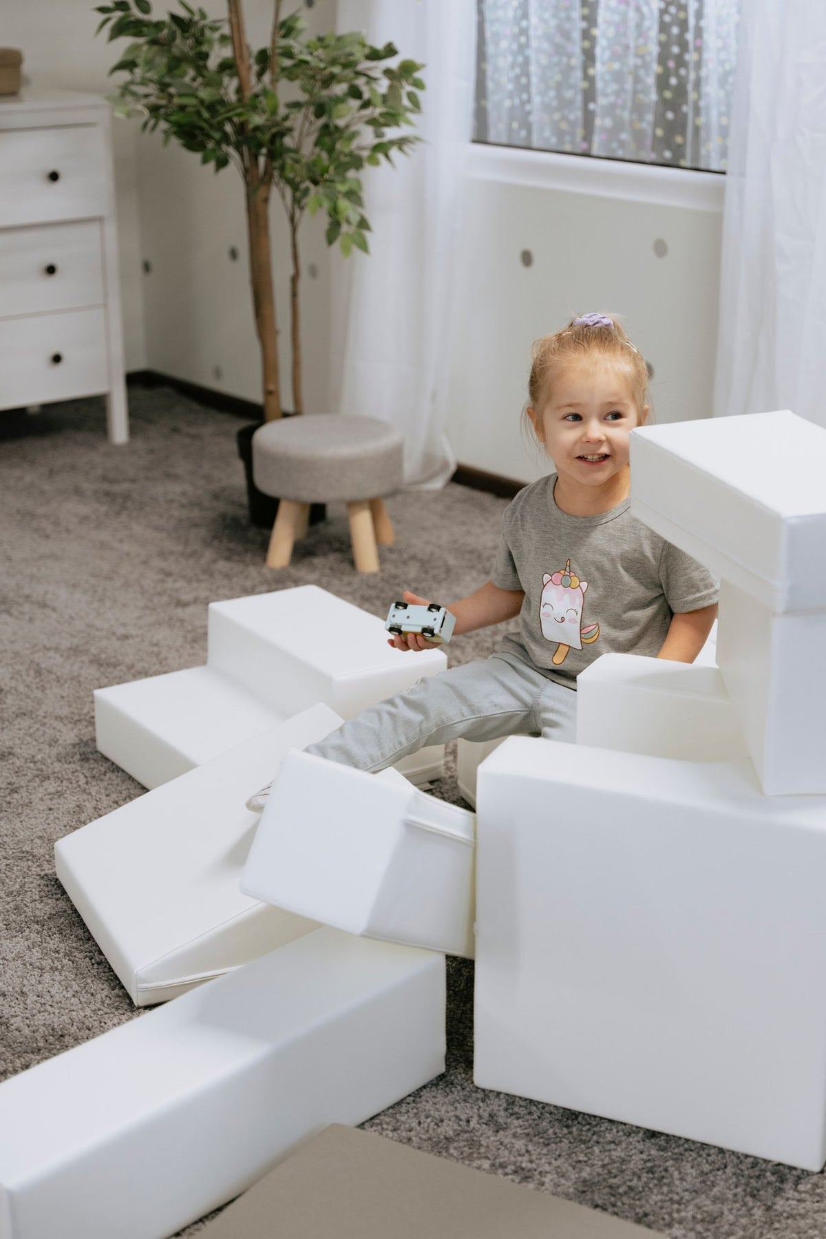 1. Child sitting on white foam blocks in a playroom, part of IGLU Adventurer 10-piece set