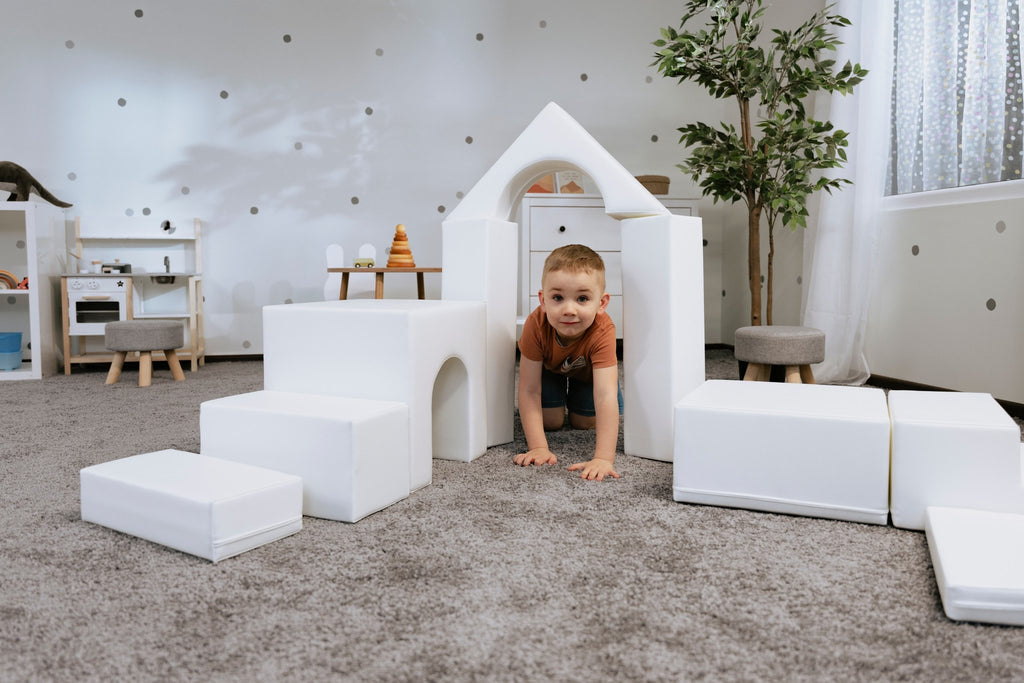 1. Child playing with white foam blocks in a playroom, part of IGLU Adventurer 10-piece set