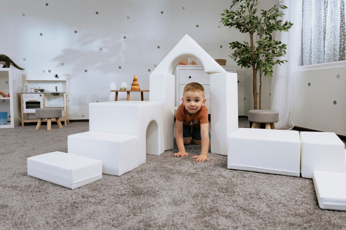 1. Child playing with white foam blocks in a playroom, part of IGLU Adventurer 10-piece set