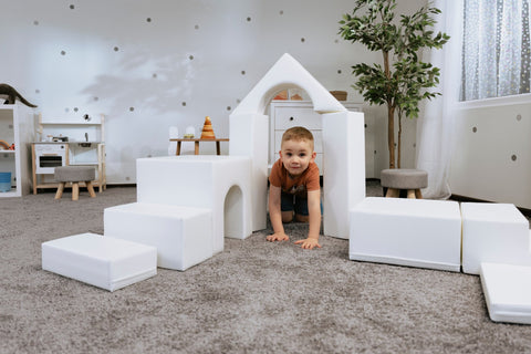 1. Child playing with white foam blocks in a playroom, part of IGLU Adventurer 10-piece set