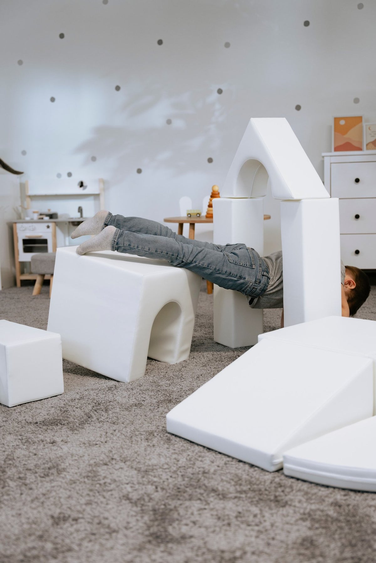 1. Child lying on white foam blocks in a playroom, part of IGLU Adventurer set