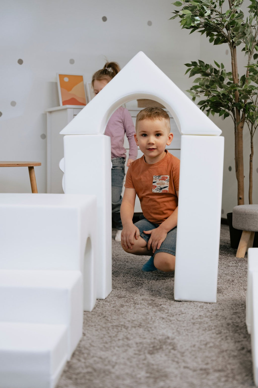 1. Child sitting inside a white foam block archway in a playroom, part of IGLU Adventurer set
