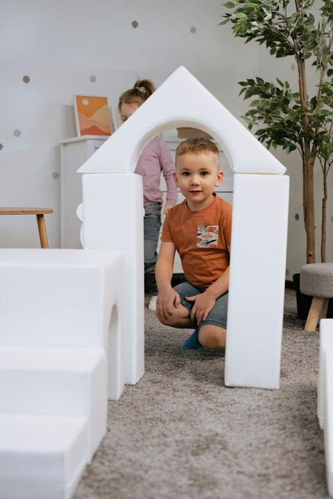 1. Child sitting inside a white foam block archway in a playroom, part of IGLU Adventurer set