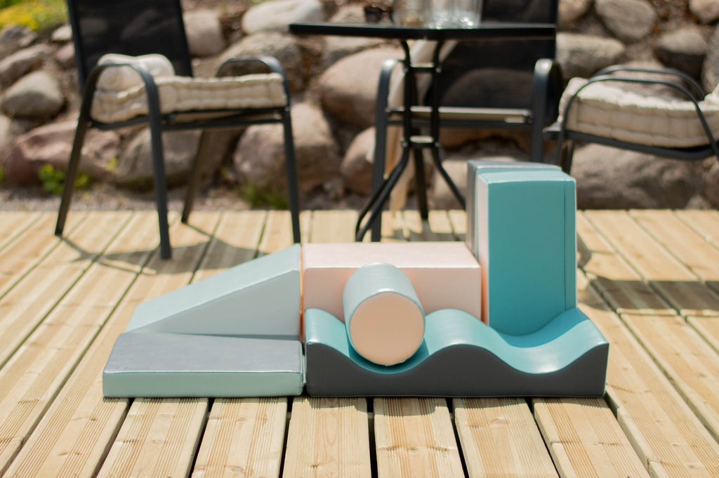 1. IGLU Discoverer 7-piece foam block set in light pastel colors on a wooden deck with chairs and rocks in the background