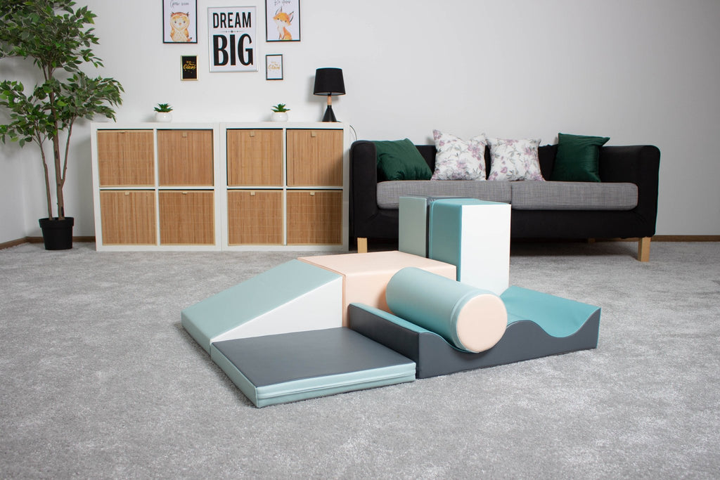 1. IGLU Discoverer 7-piece foam block set in light pastel colors on a grey carpet in a living room setting with a sofa and decor in the background