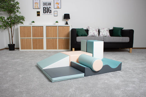 1. IGLU Discoverer 7-piece foam block set in light pastel colors on a grey carpet in a living room setting with a sofa and decor in the background