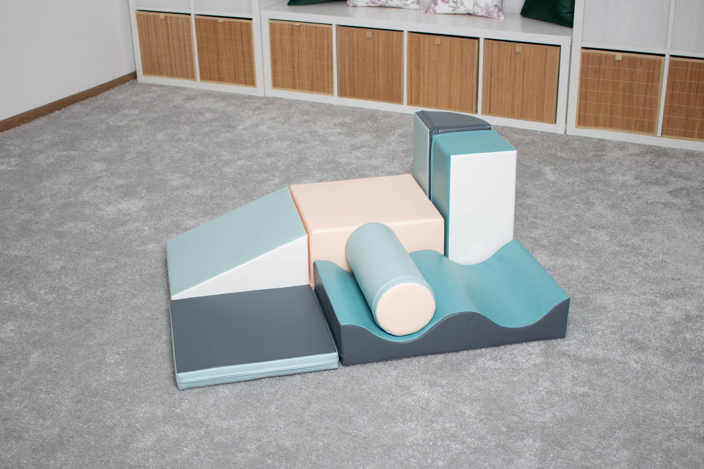 1. IGLU Discoverer 7-piece foam block set in light pastel colors arranged on a grey carpet in a room with storage units in the background