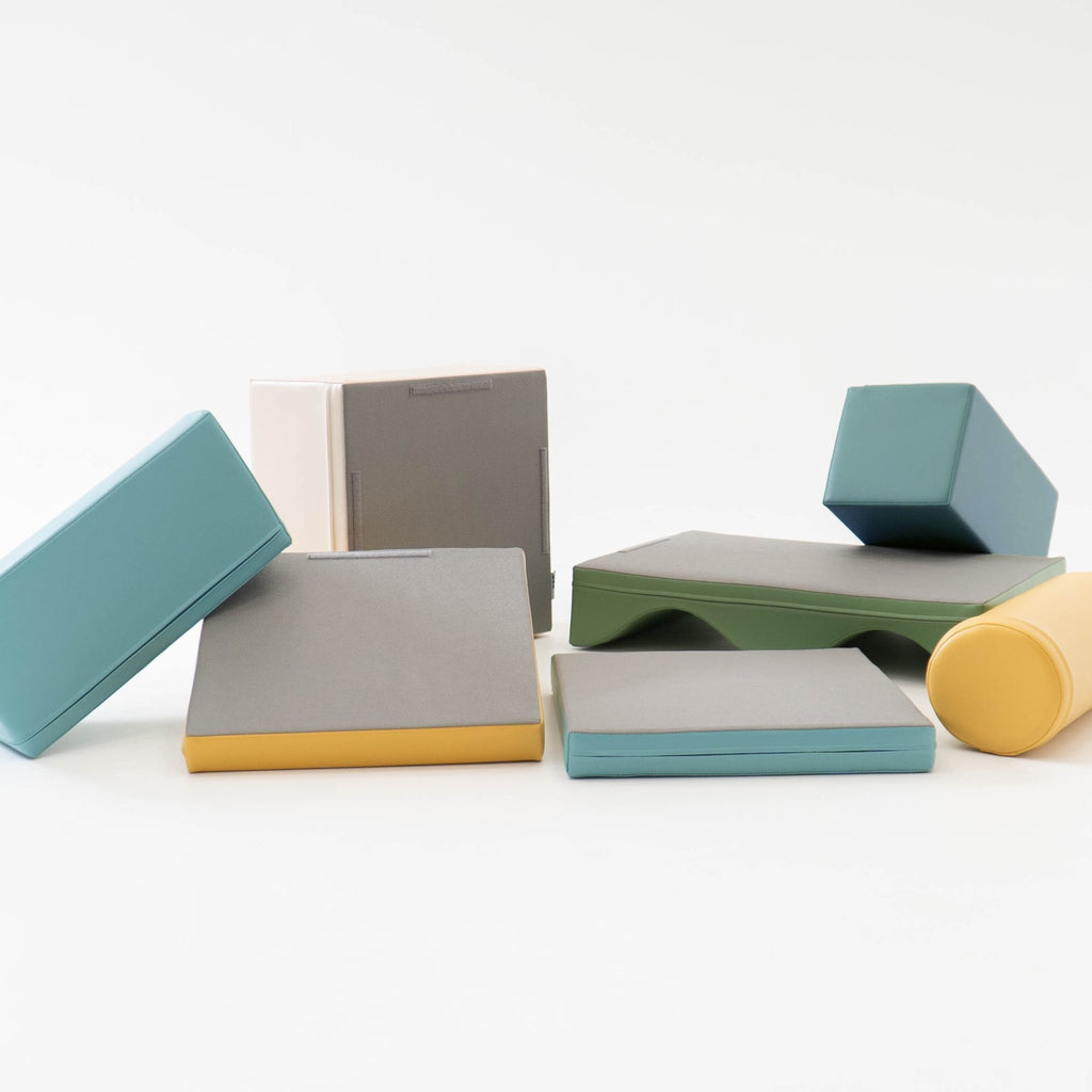 4. IGLU Discoverer foam blocks scattered in pastel turquoise, yellow, and green on a white background