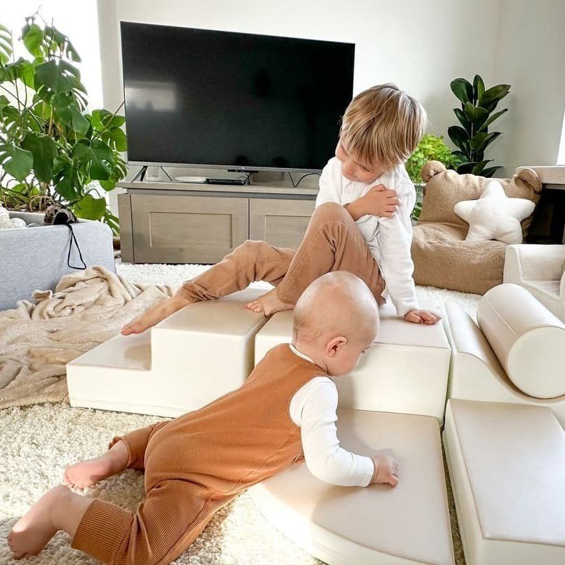 1. Two children playing on beige IGLU foam blocks in a cozy living room setting