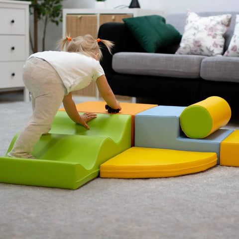 1. Toddler climbing on IGLU Explorer foam block set in light multicolor in a living room setting