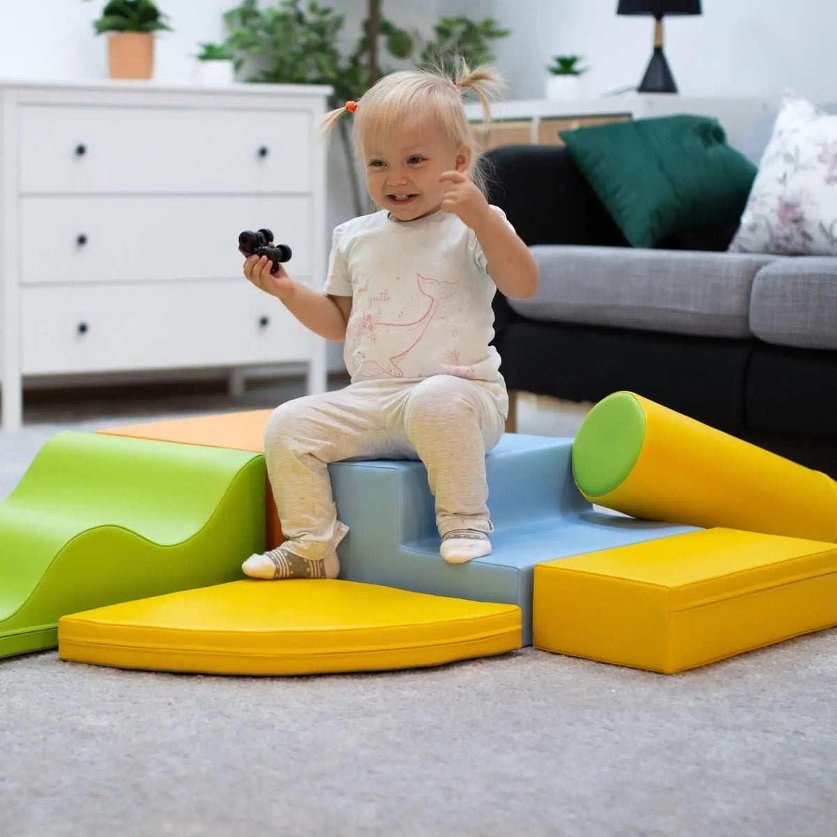 1. Toddler sitting on IGLU Explorer foam block set in light multicolor in a living room