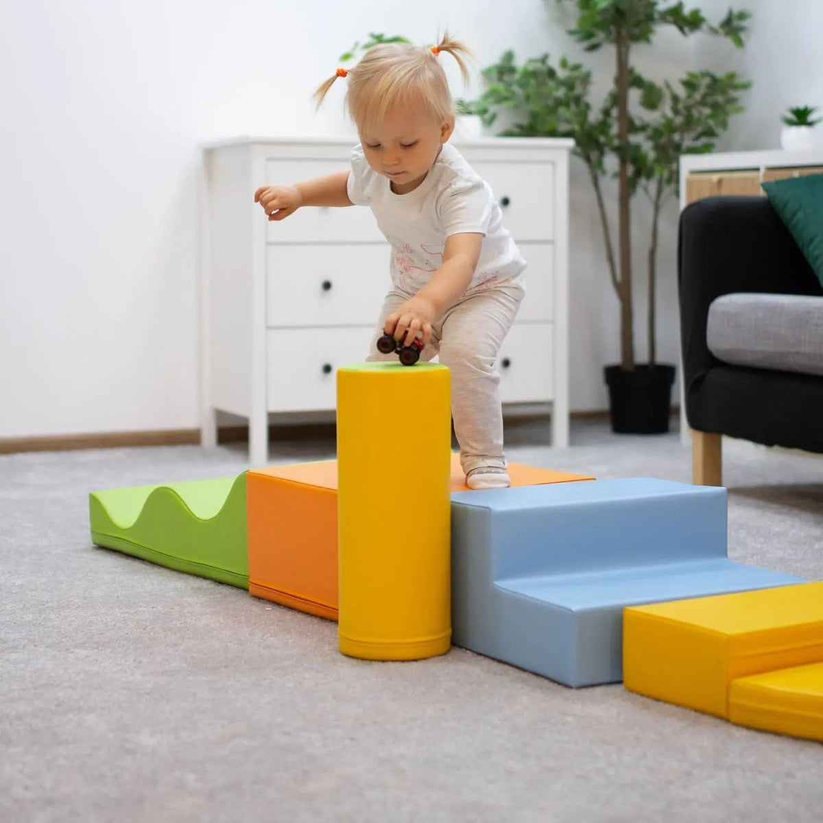1. Toddler balancing on IGLU Explorer foam block set in light multicolor in a living room