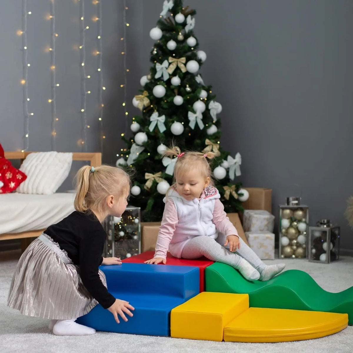 1. Two girls playing with multicolor foam blocks near Christmas tree