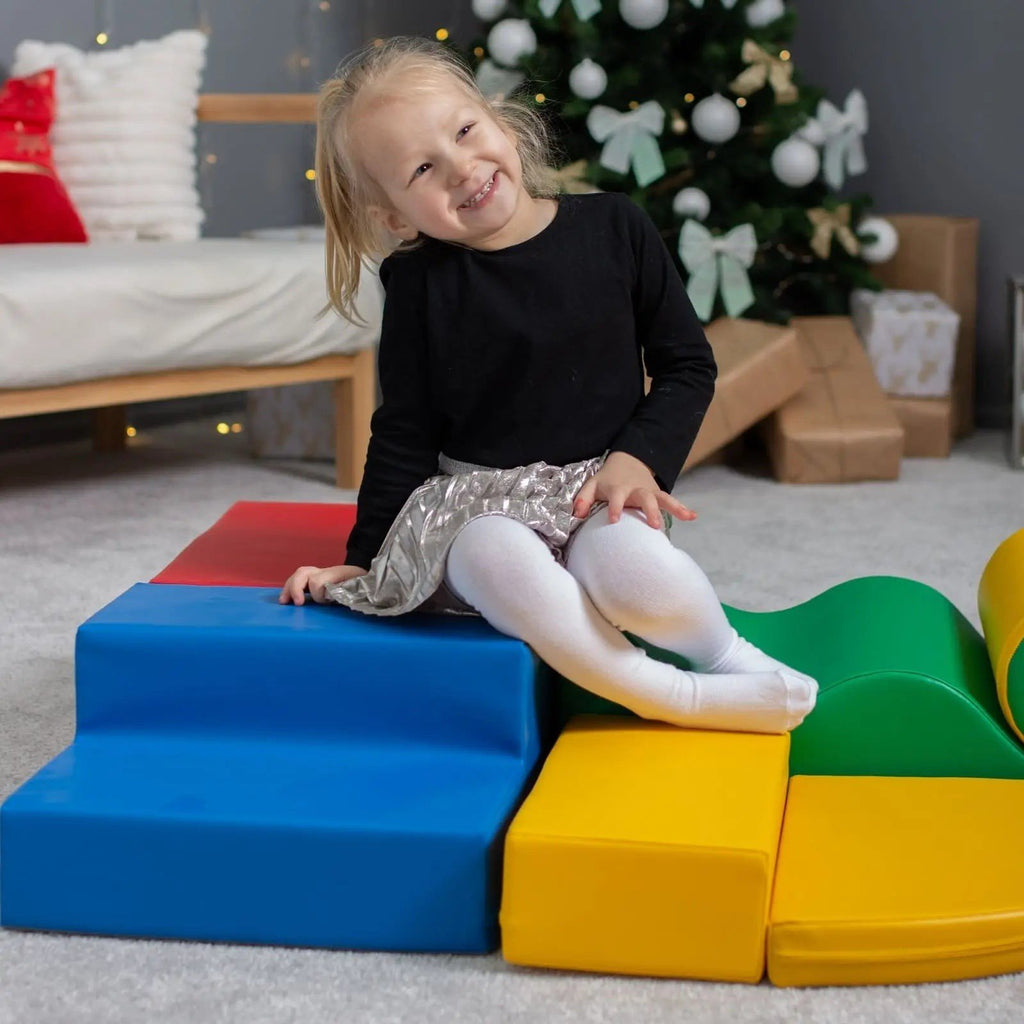 1. Girl sitting on multicolor foam blocks smiling in playroom