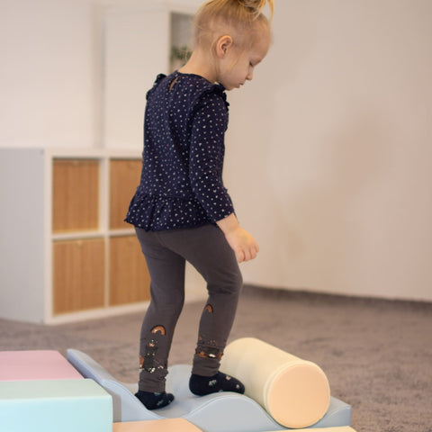 1. Child balancing on pastel foam blocks in a playroom