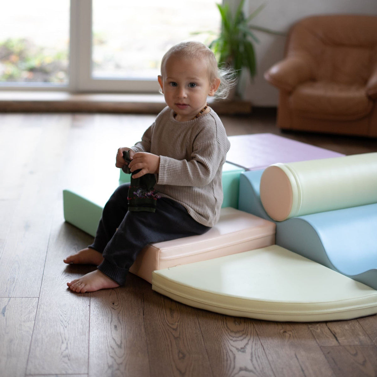 1. Toddler sitting on pastel foam blocks holding a toy