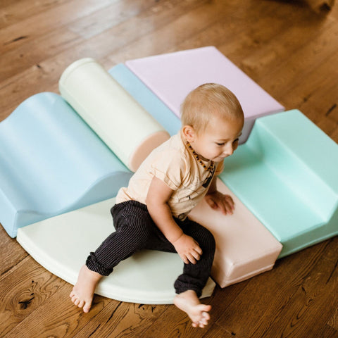 1. Child sitting on pastel foam blocks on a wooden floor
