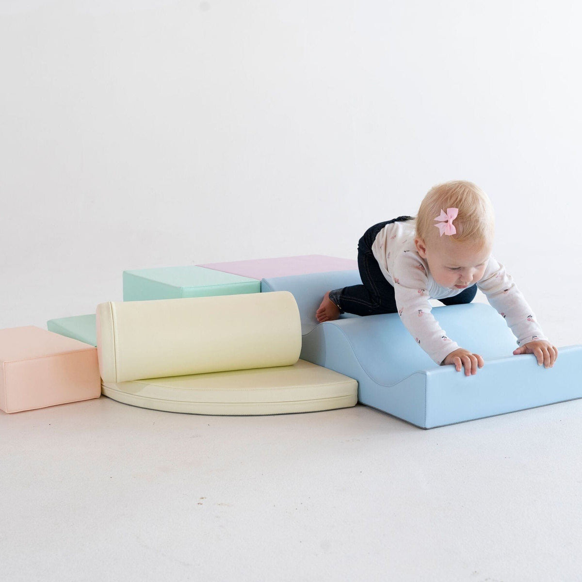 1. Child climbing on pastel foam blocks in a studio
