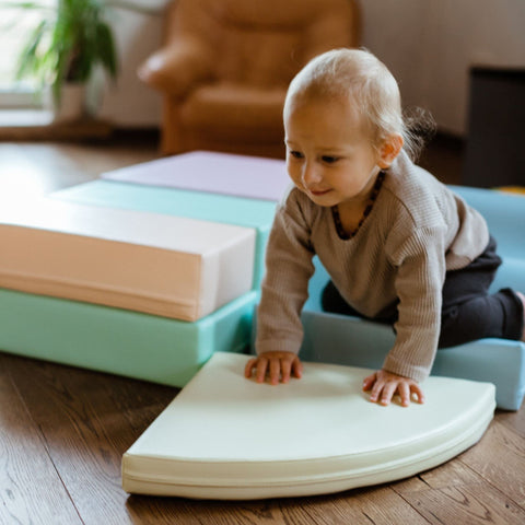 1. Toddler crawling on pastel foam blocks in a living room