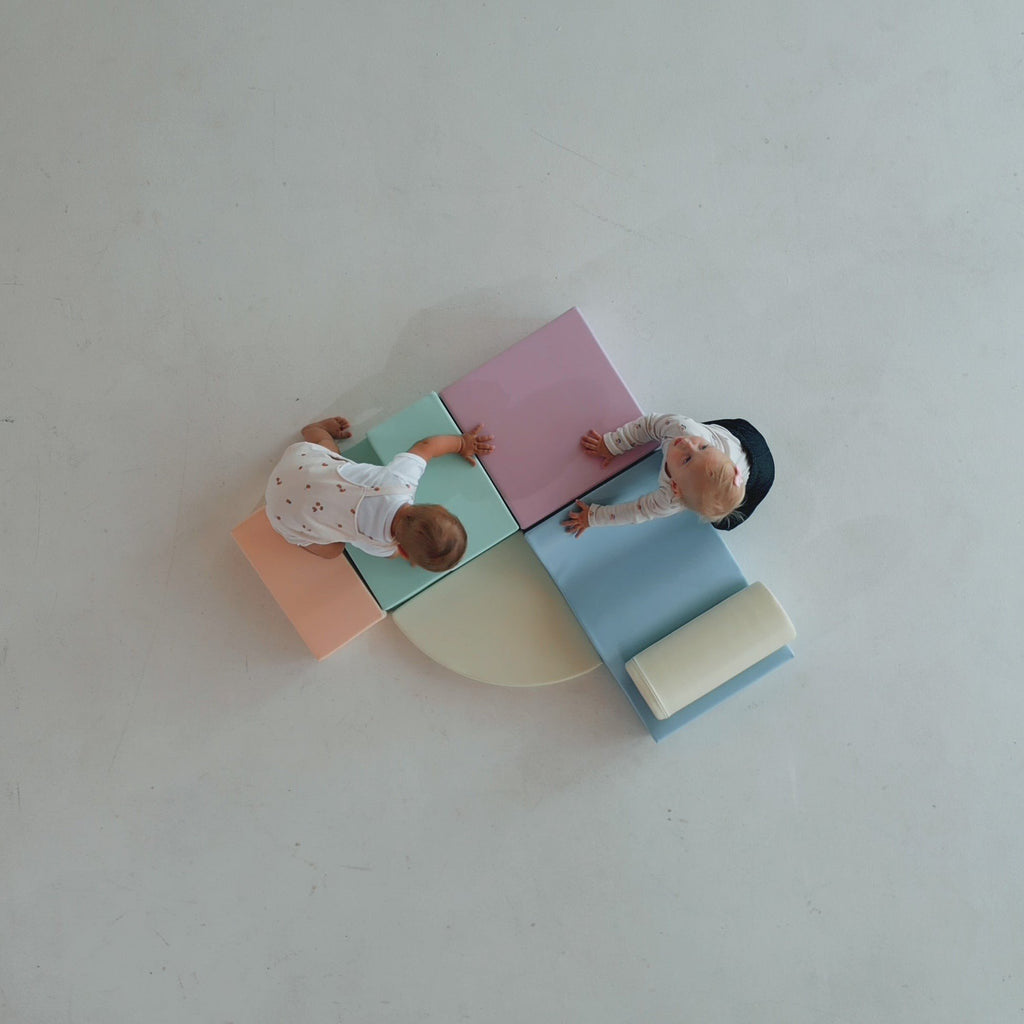 1. Two toddlers playing on pastel foam blocks viewed from above