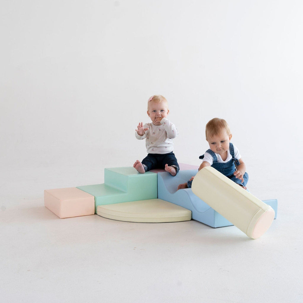 1. Two children playing on pastel foam blocks in a studio