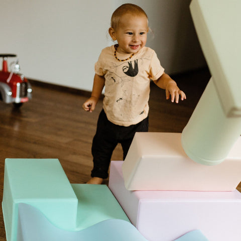 1. Smiling toddler standing among pastel foam blocks