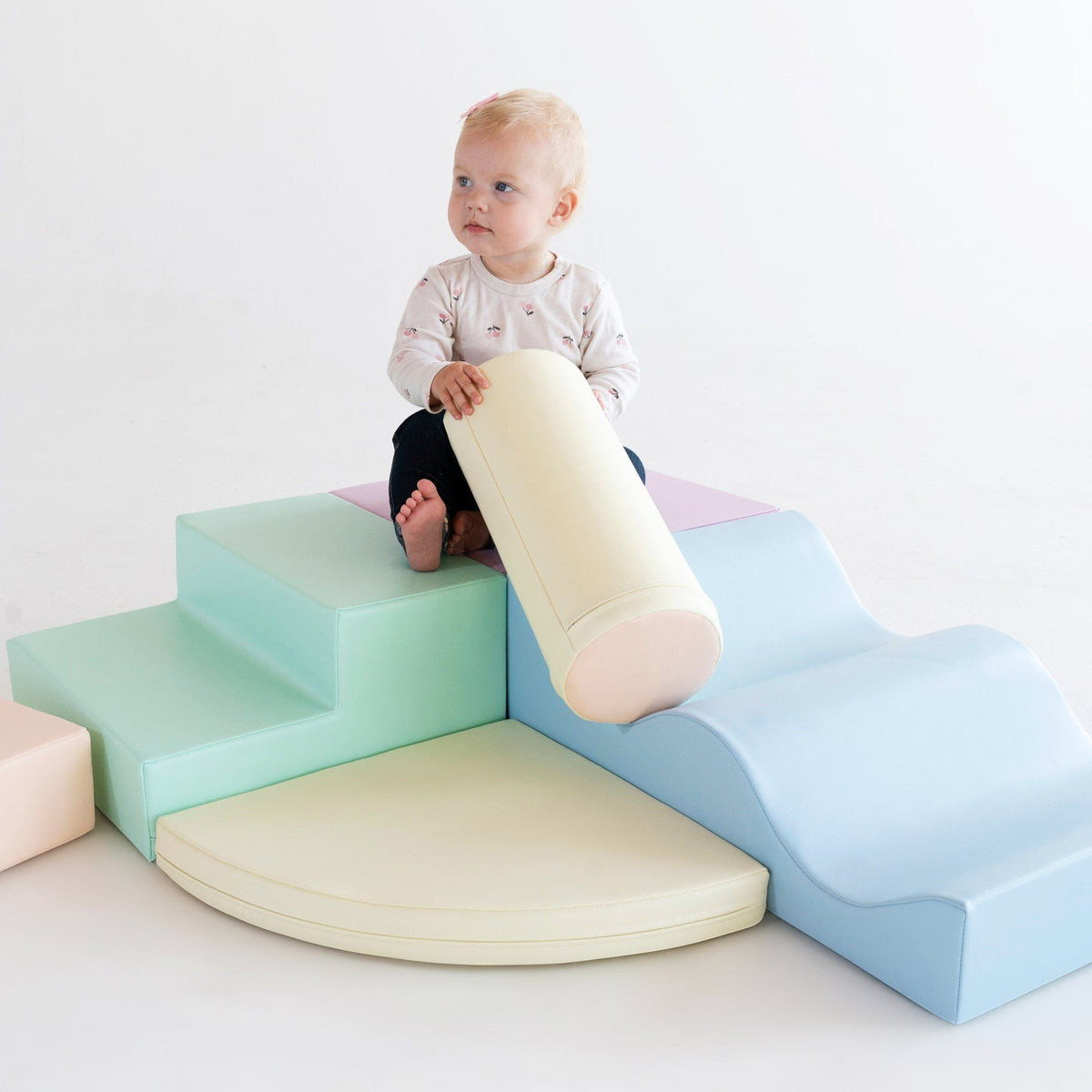 1. Toddler sitting on pastel foam blocks in a studio