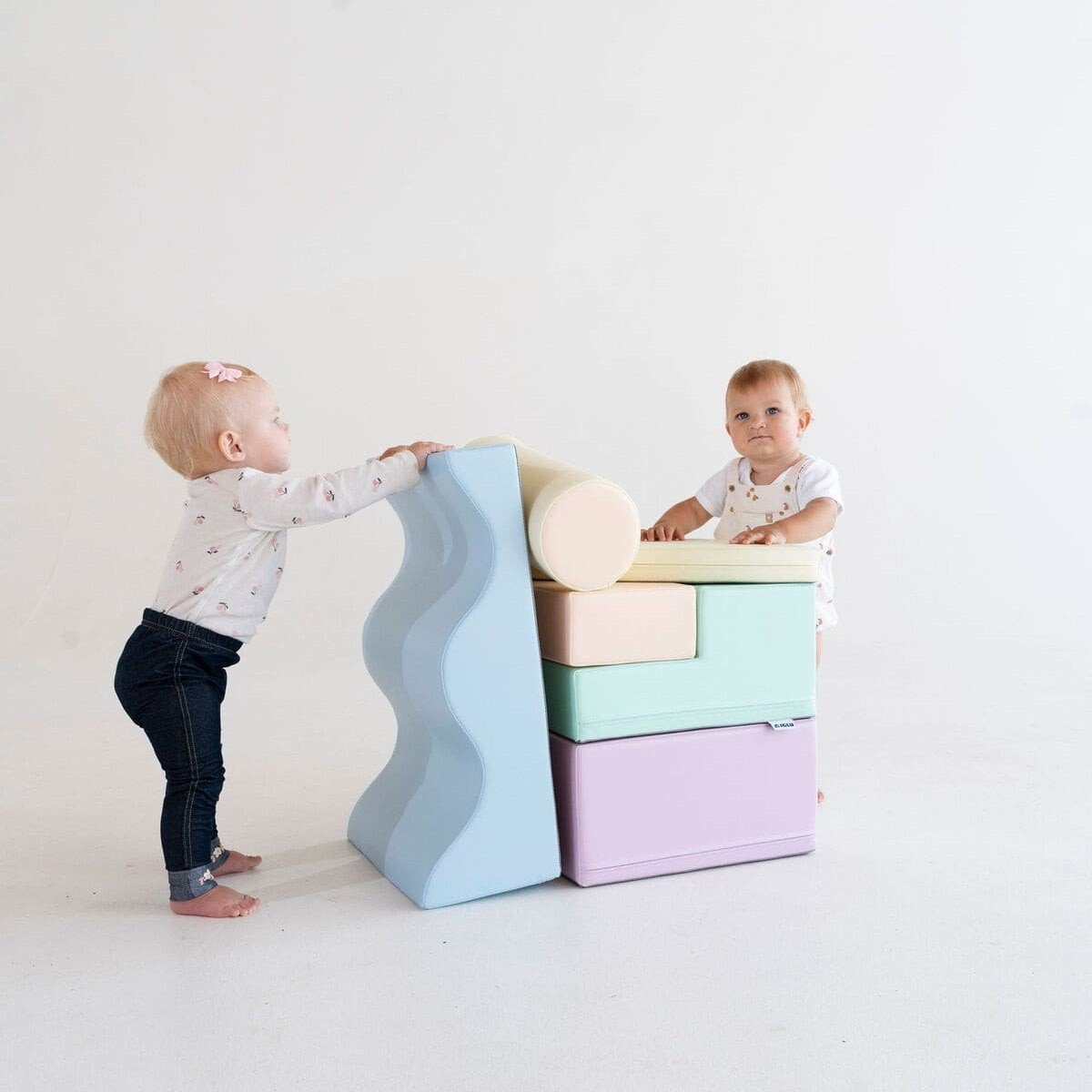 1. Two toddlers playing with pastel foam blocks in a studio
