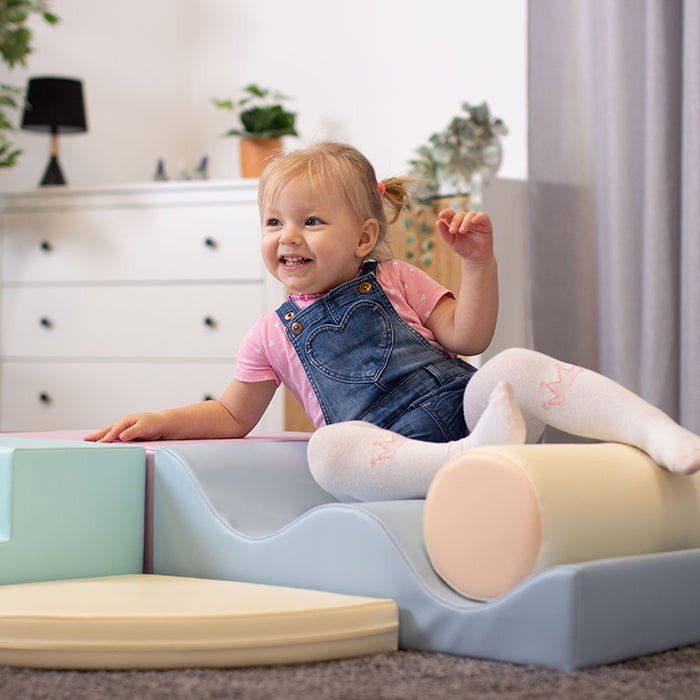 1. Toddler sitting on pastel foam blocks in a living room