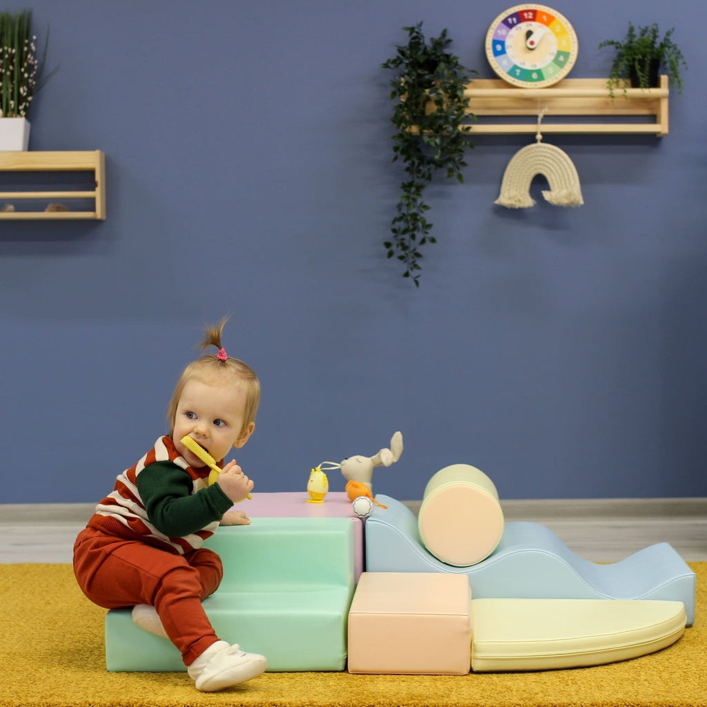 1. Toddler leaning on pastel foam blocks in a colorful playroom
