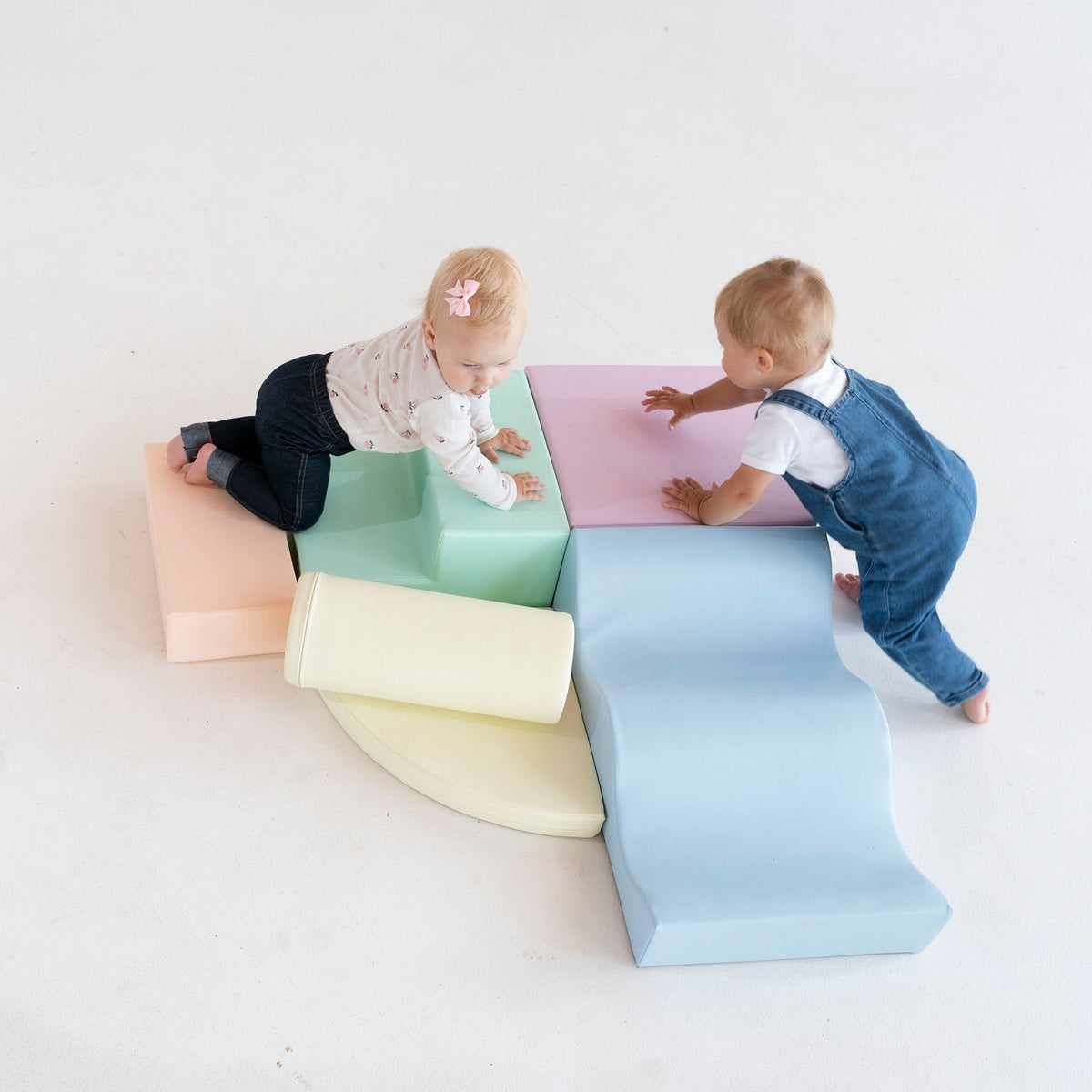 1. Two children playing on pastel foam blocks in a studio