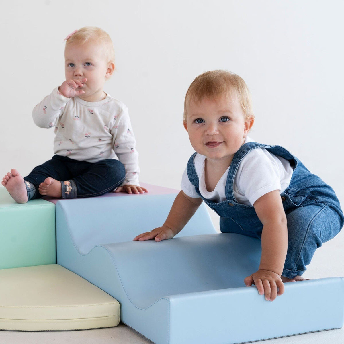 1. Two toddlers playing on pastel foam blocks in a studio