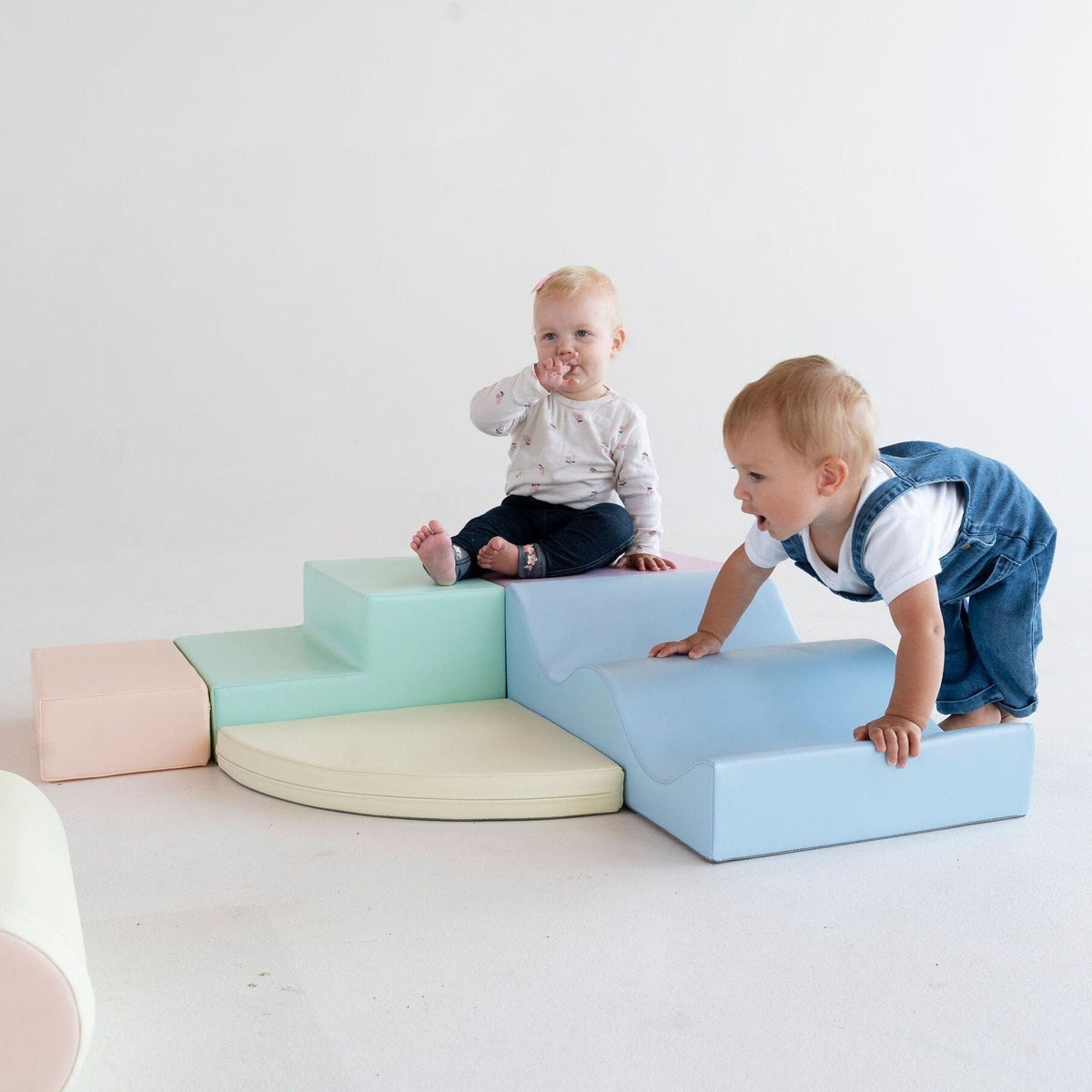 1. Two children playing on pastel foam blocks in a studio